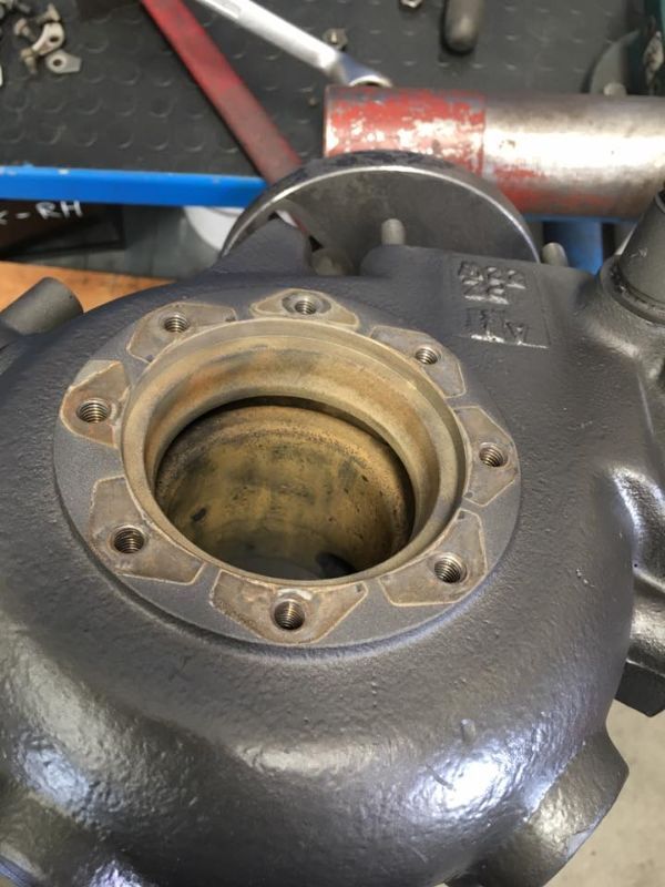 Vista ravvicinata di un componente automobilistico in metallo fuso, probabilmente l'alloggiamento di un turbocompressore, che mostra un'apertura circolare con fori per bulloni.