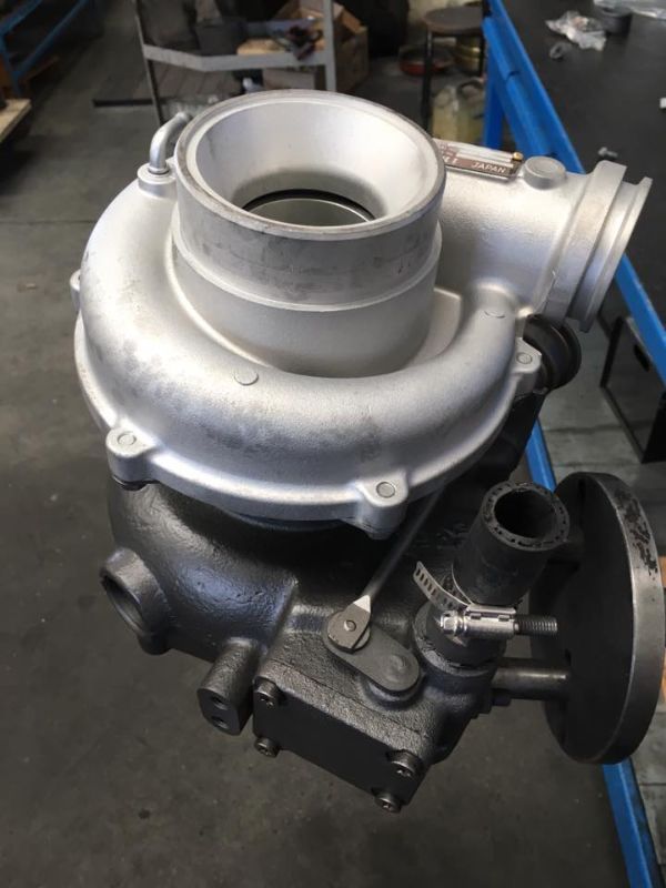 Vista dall'alto di un turbocompressore automobilistico metallico con alloggiamento del compressore argentato su un alloggiamento della turbina scuro e ruvido.
