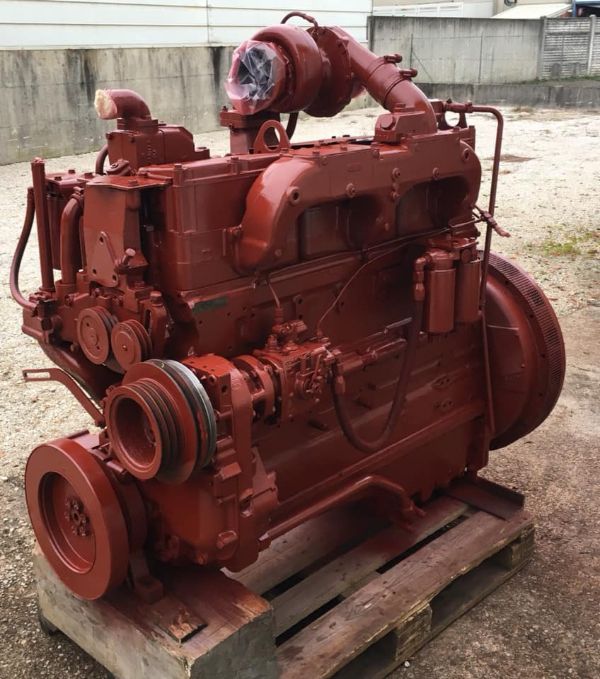 Un motore diesel industriale, appena verniciato di rosso scuro, è appoggiato su un pallet di legno all'aperto.
