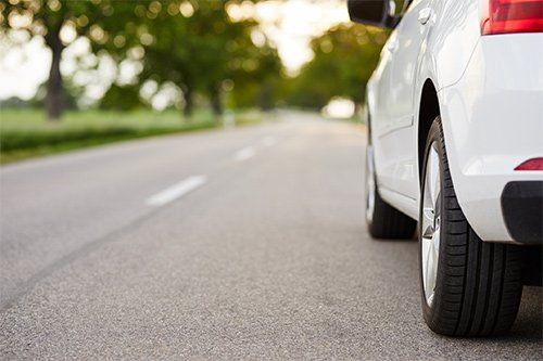 A white car is parked on the side of a road.
