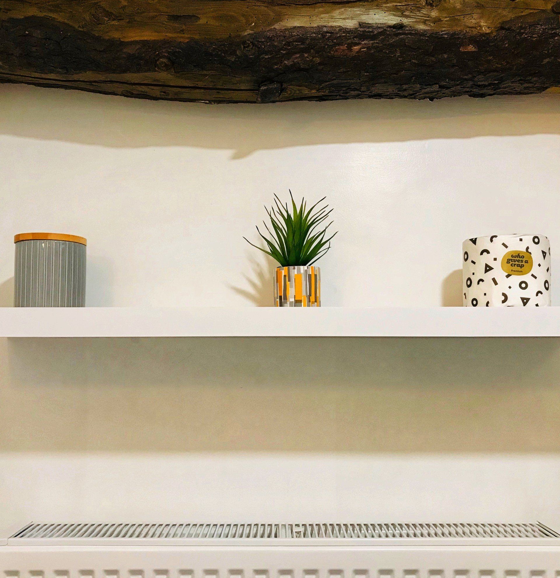 White shelf with topiary and large wooden beam overhead