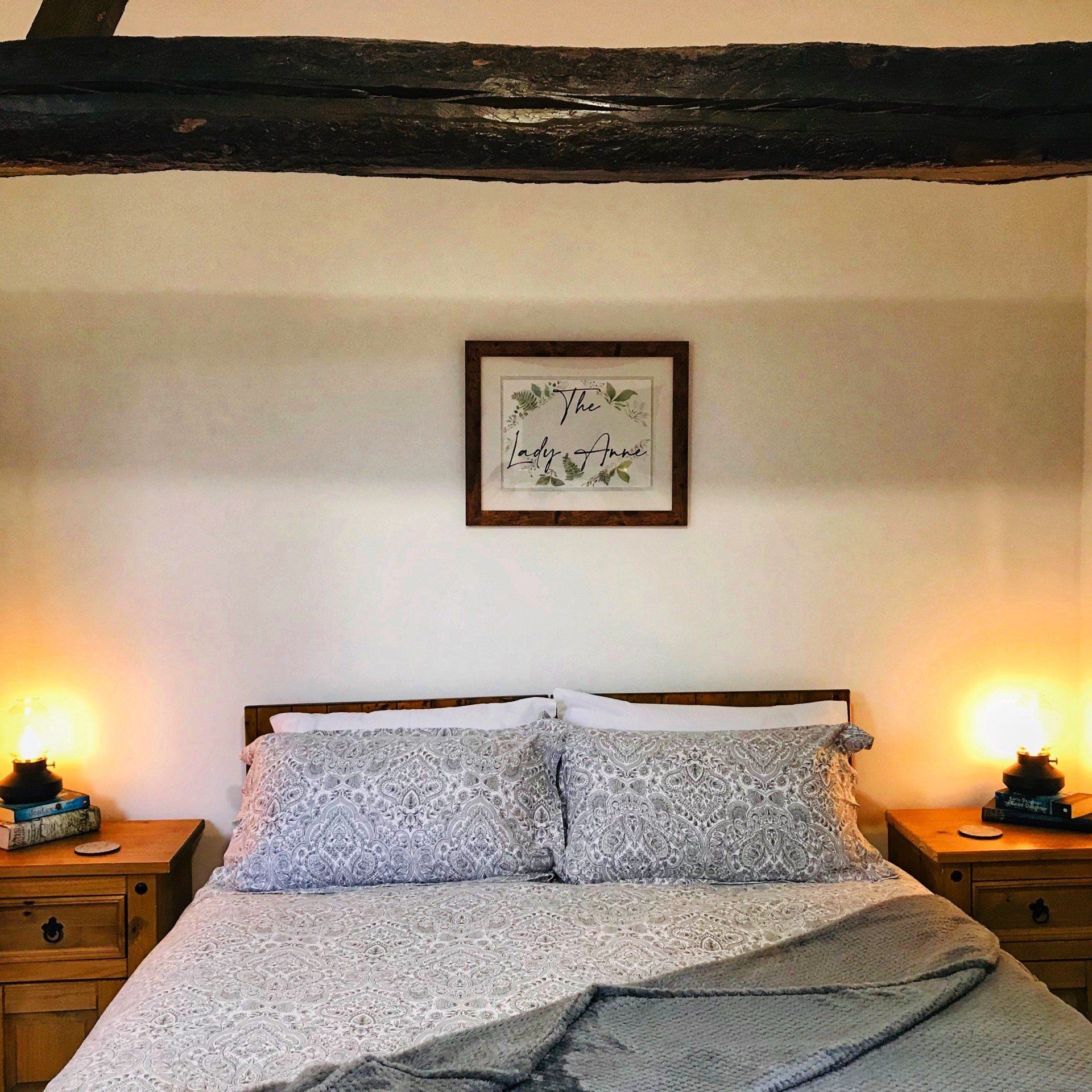 Traditional double bed with patterned duvet and large wooden beam overhead