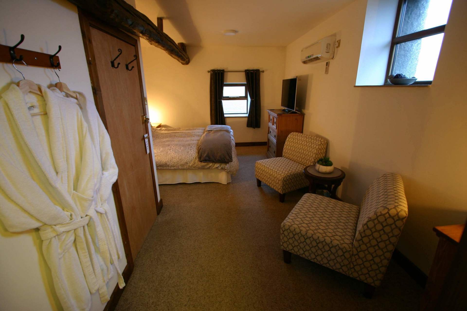 Long shot of Lady Anne room including 2 comfy chairs and large bed with duvet