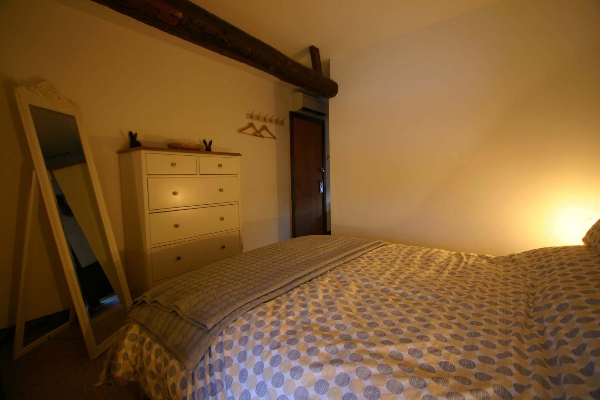 Comfy double bed with duvet, white chest of drawers with mirror and large wooden beam overhead