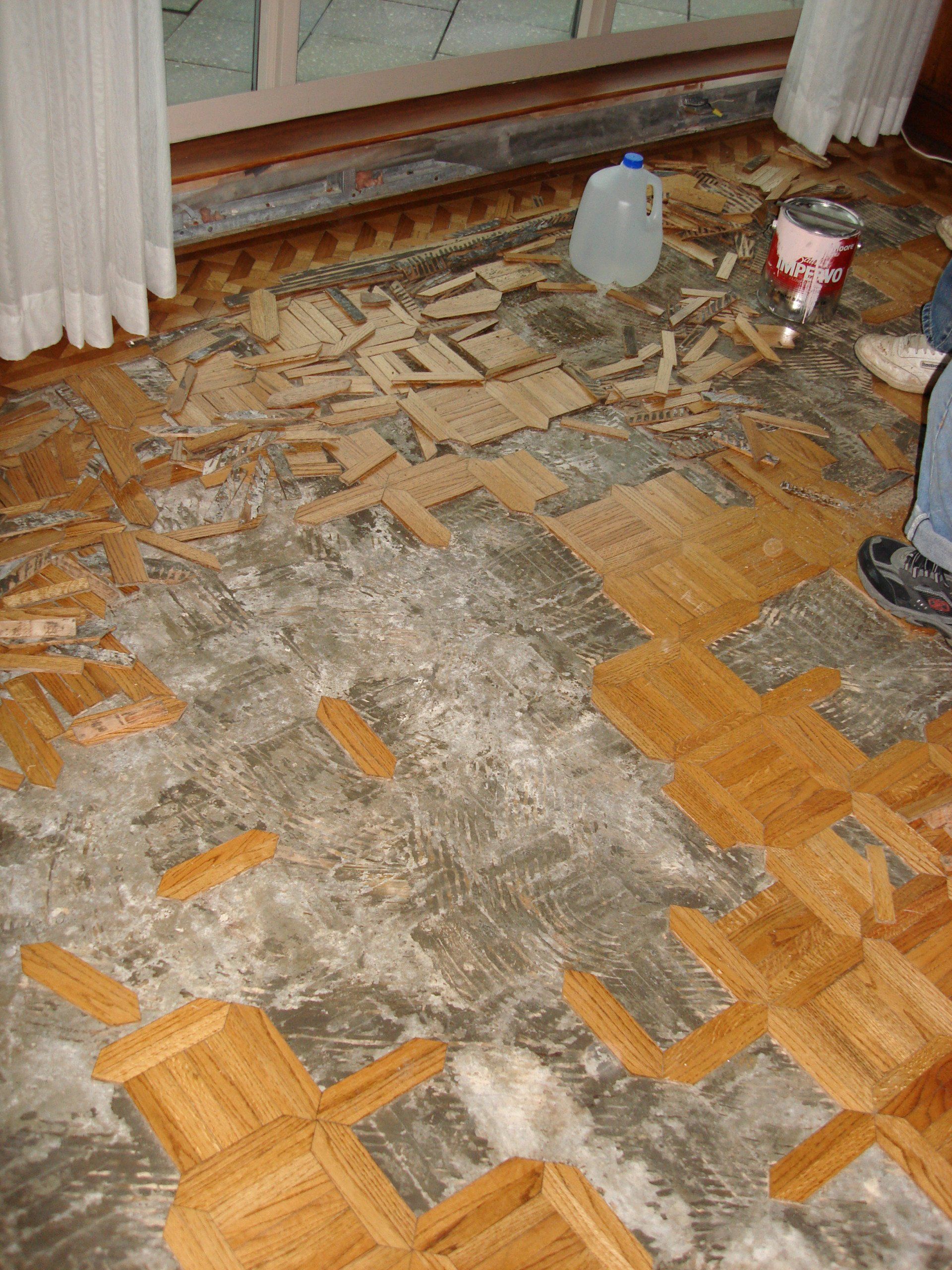 A person is standing on a wooden floor next to a bucket of paint
