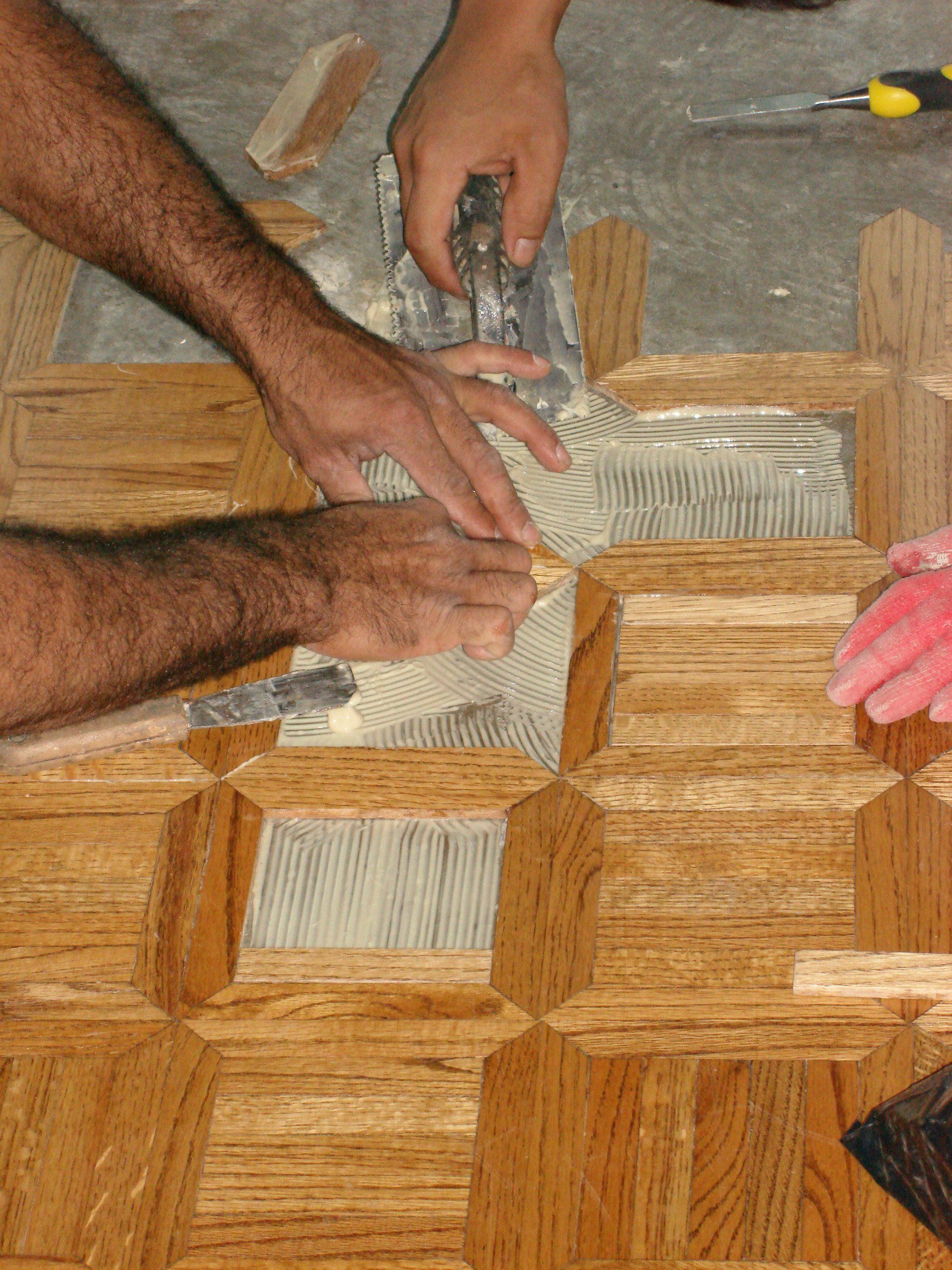 A man is working on a wooden floor with a trowel