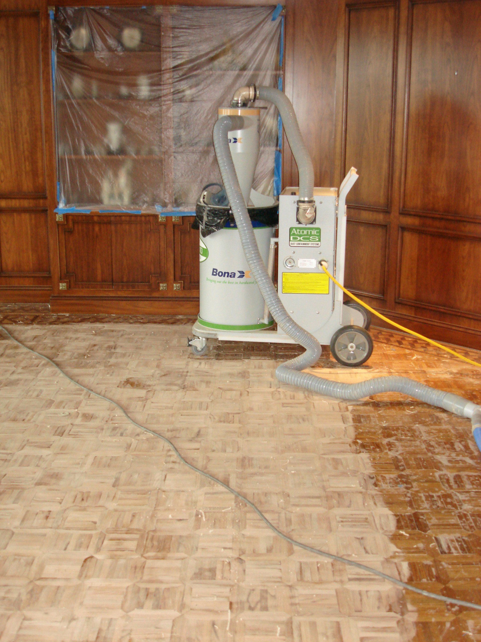 A vacuum cleaner is being used to clean a wooden floor