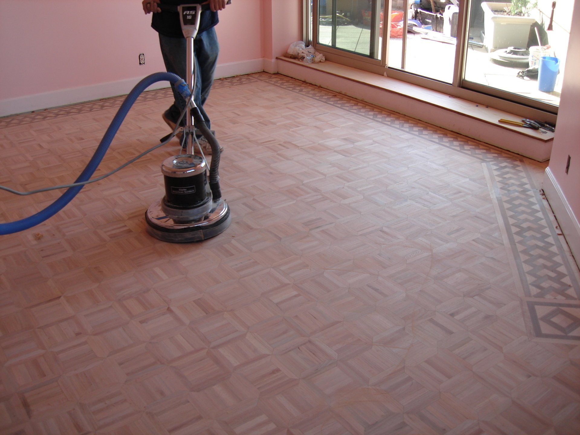 A man is using a machine to sand a wooden floor