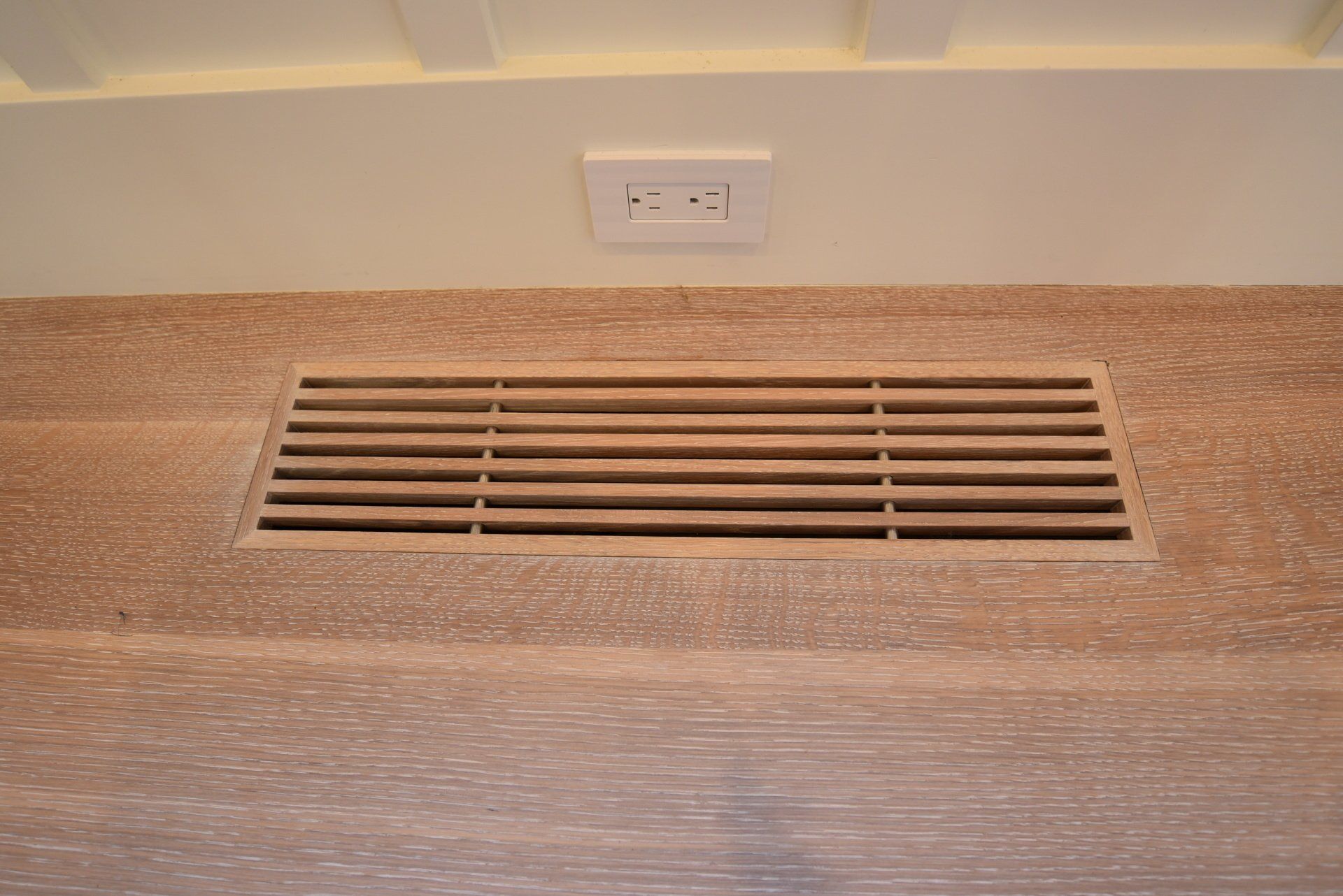 A wooden floor with a ventilation grate on it