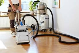 A man is using a vacuum cleaner to clean a wooden floor.