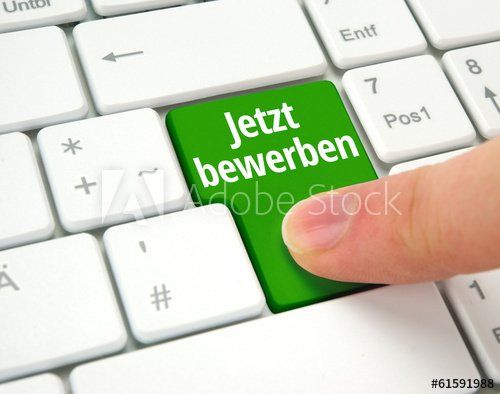 A person is pressing a green button on a keyboard that says jetzt bewerben