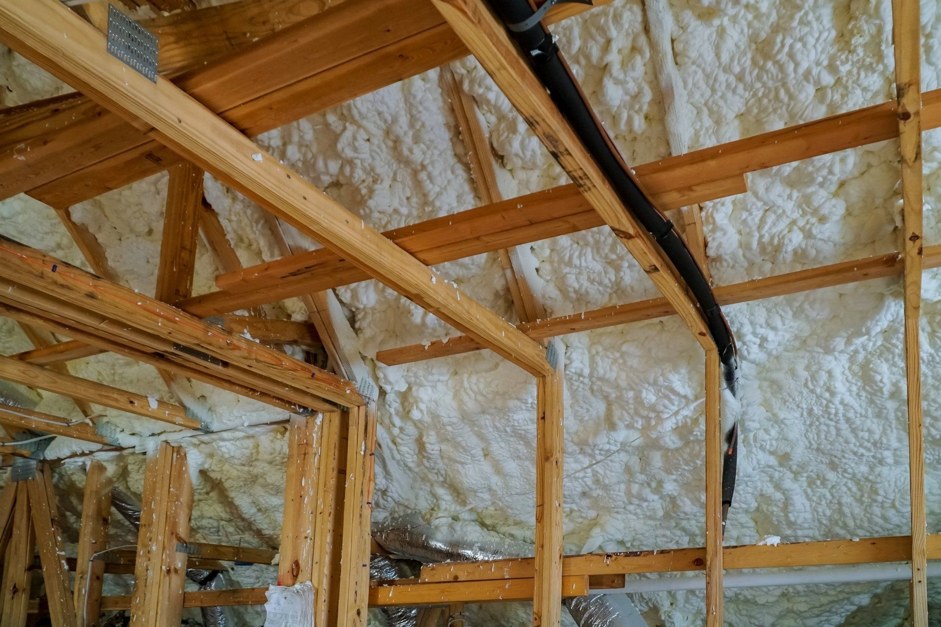 Interior roof framing with wooden beams and reflective insulation under construction