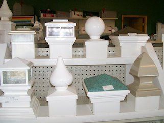 White decorative fence post caps displayed on a shelf in a store.