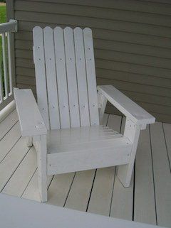 White Adirondack chair on a porch with white railing and siding.