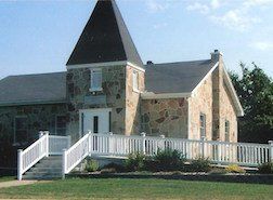 Stone building with a black steeple, white railing, and ramp.
