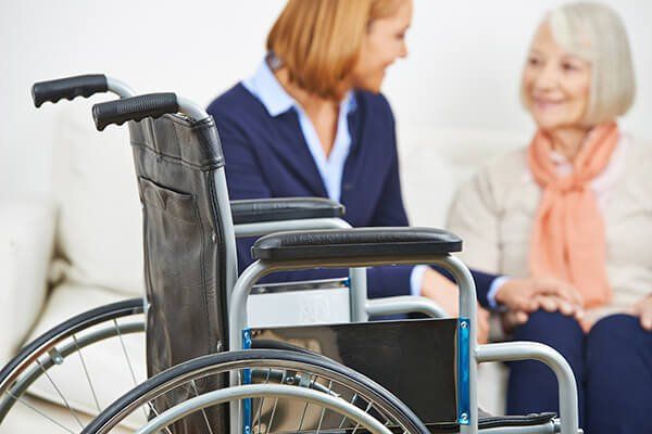 Elderly disabled woman being helped by a carer