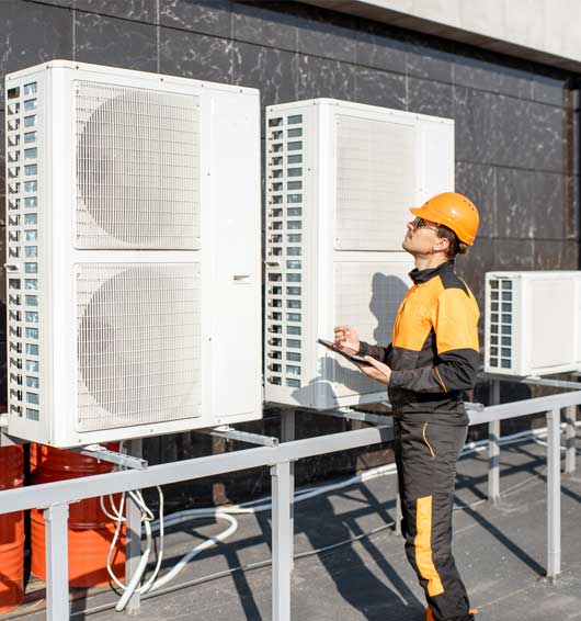 Workman Servicing Air Conditioning with Tablet — Zachary, LA — Hughes Mechanical Contractors Workman Servicing Air Conditioning with Tablet — Zachary, LA — Hughes Mechanical Contractors
