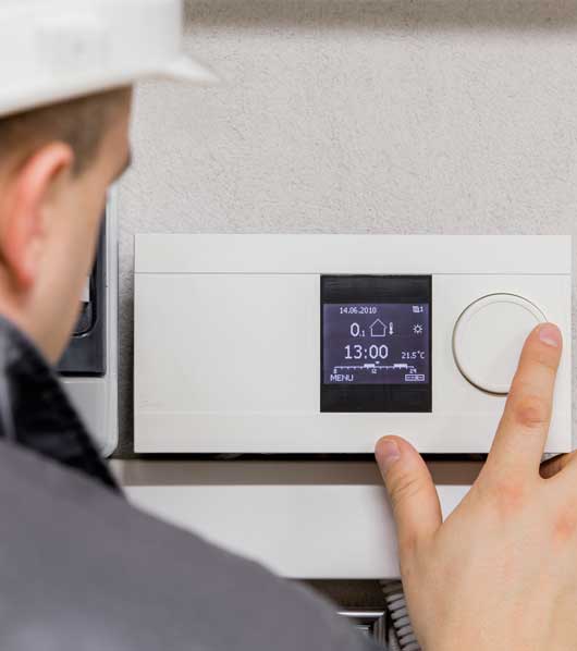 Man Adjusting Thermostat — Zachary, LA — Hughes Mechanical Contractors Man Adjusting Thermostat — Zachary, LA — Hughes Mechanical Contractors