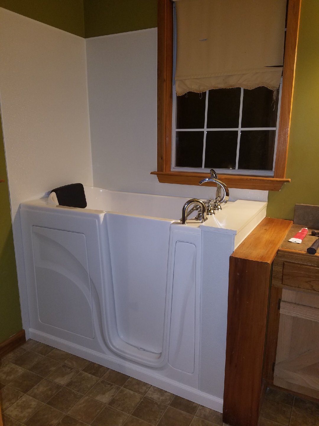 A walk in tub is in a bathroom next to a window.