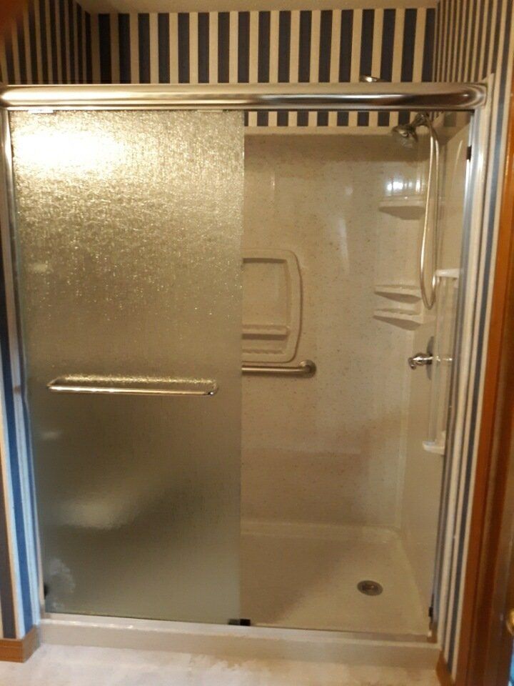 A bathroom with a striped wall and a sliding glass shower door.
