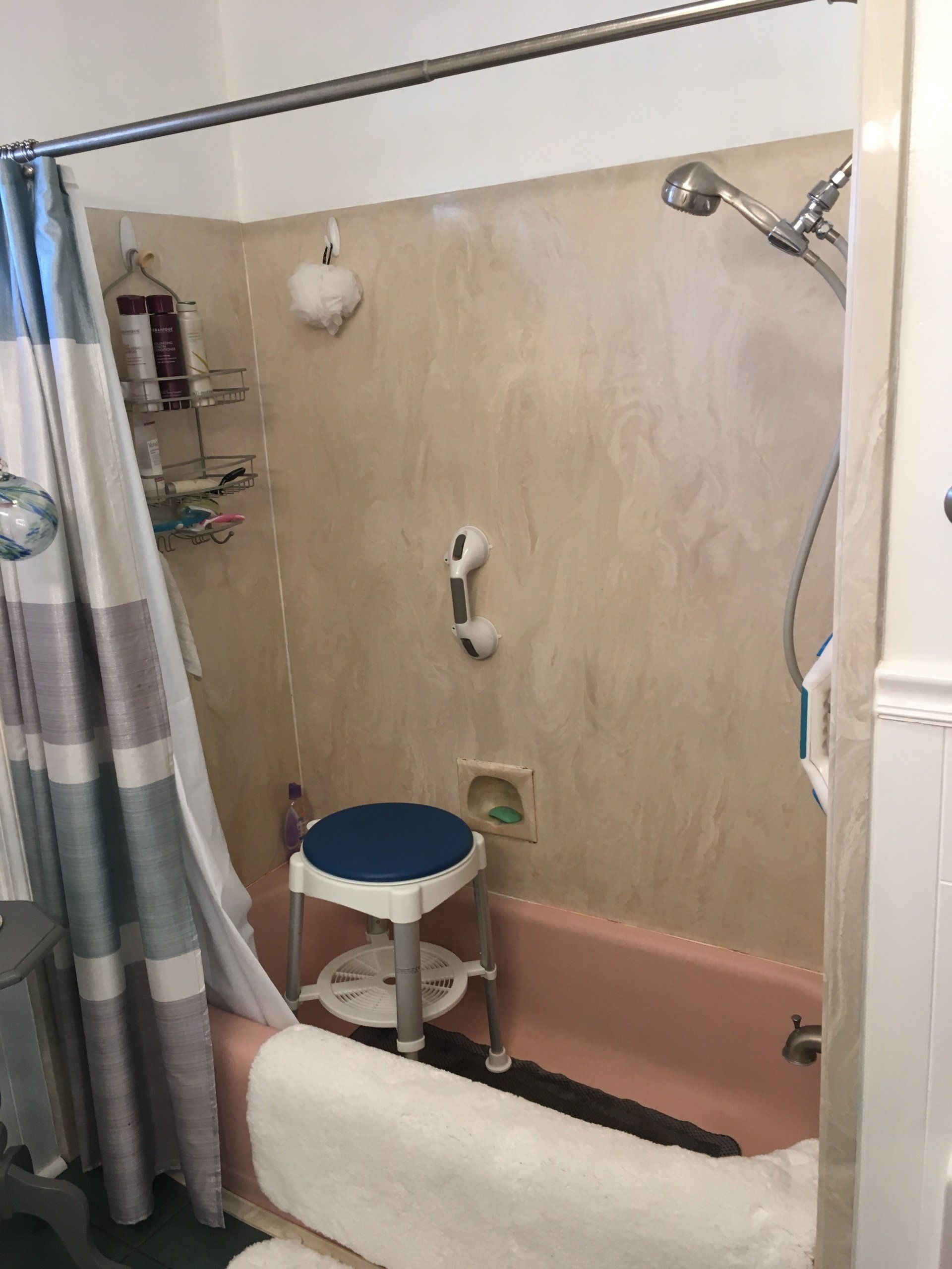 A bathroom with a bathtub , shower , and stool.