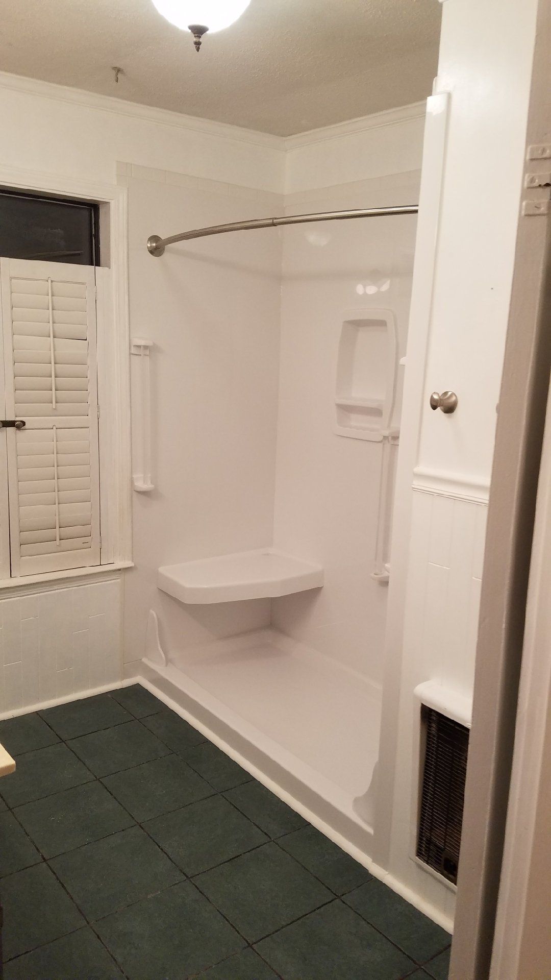 A bathroom with a walk in shower and a window.