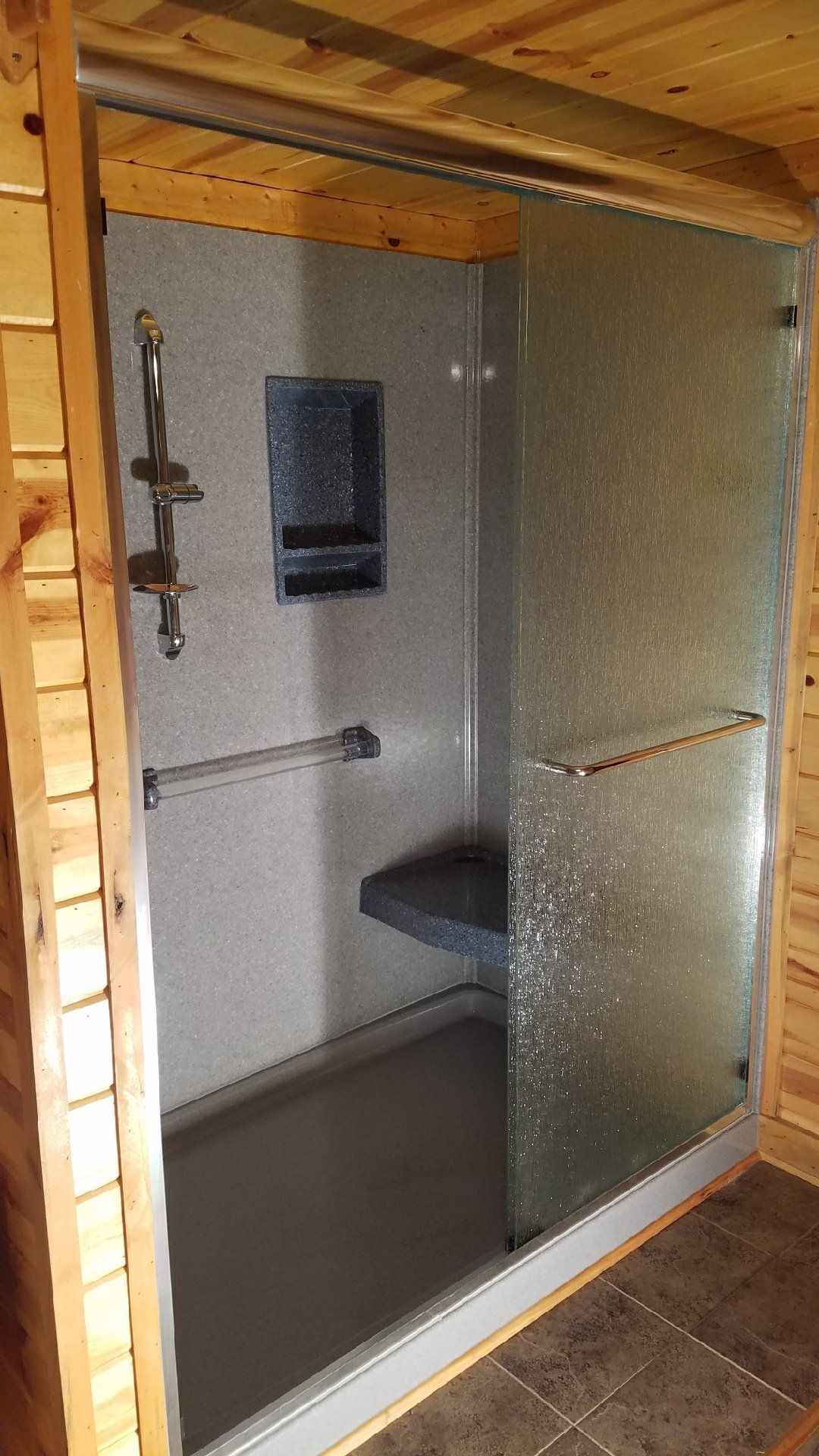 A bathroom with a walk in shower and a glass door.