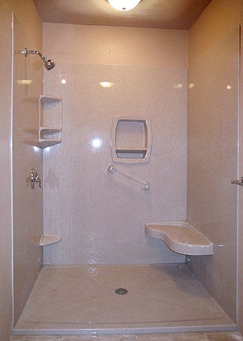 A walk in shower with a bench and a shower head.