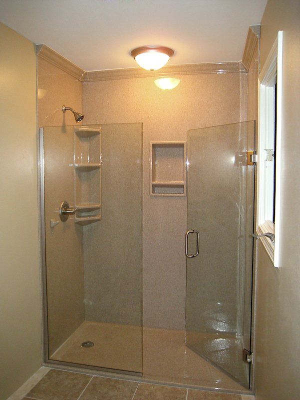 A bathroom with a walk in shower with a glass door.