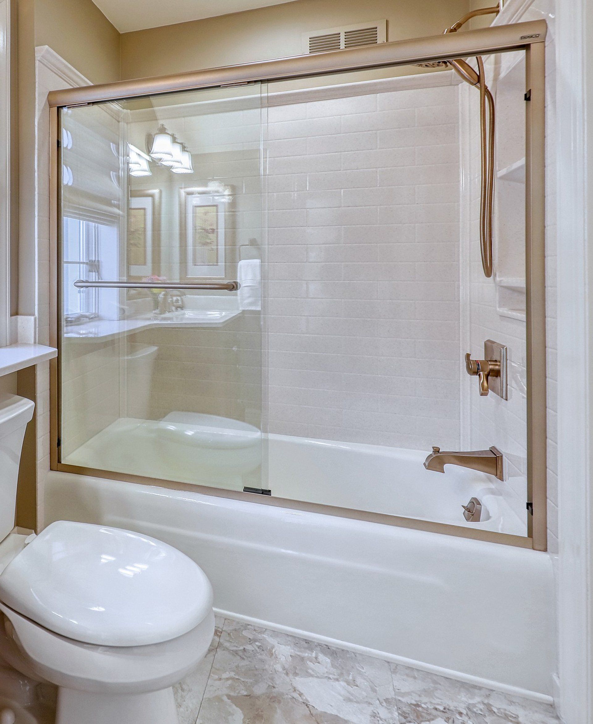 A bathroom with a bathtub , toilet , sink and shower.