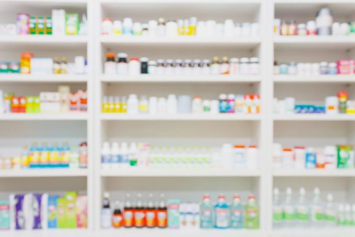 A blurred image of shelves in a pharmacy filled with lots of different types of medications.