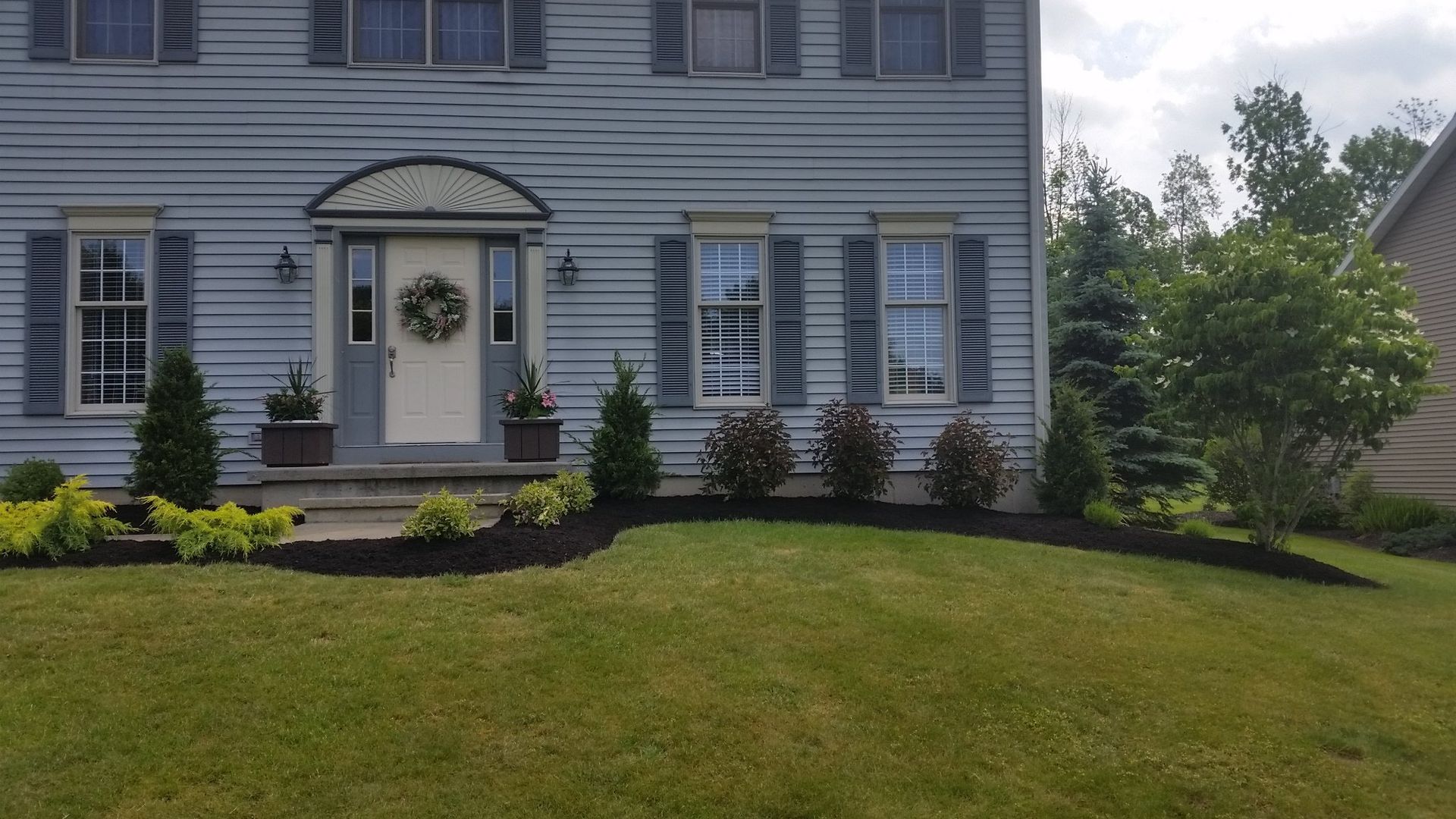 finished flowerbed in front of blue house