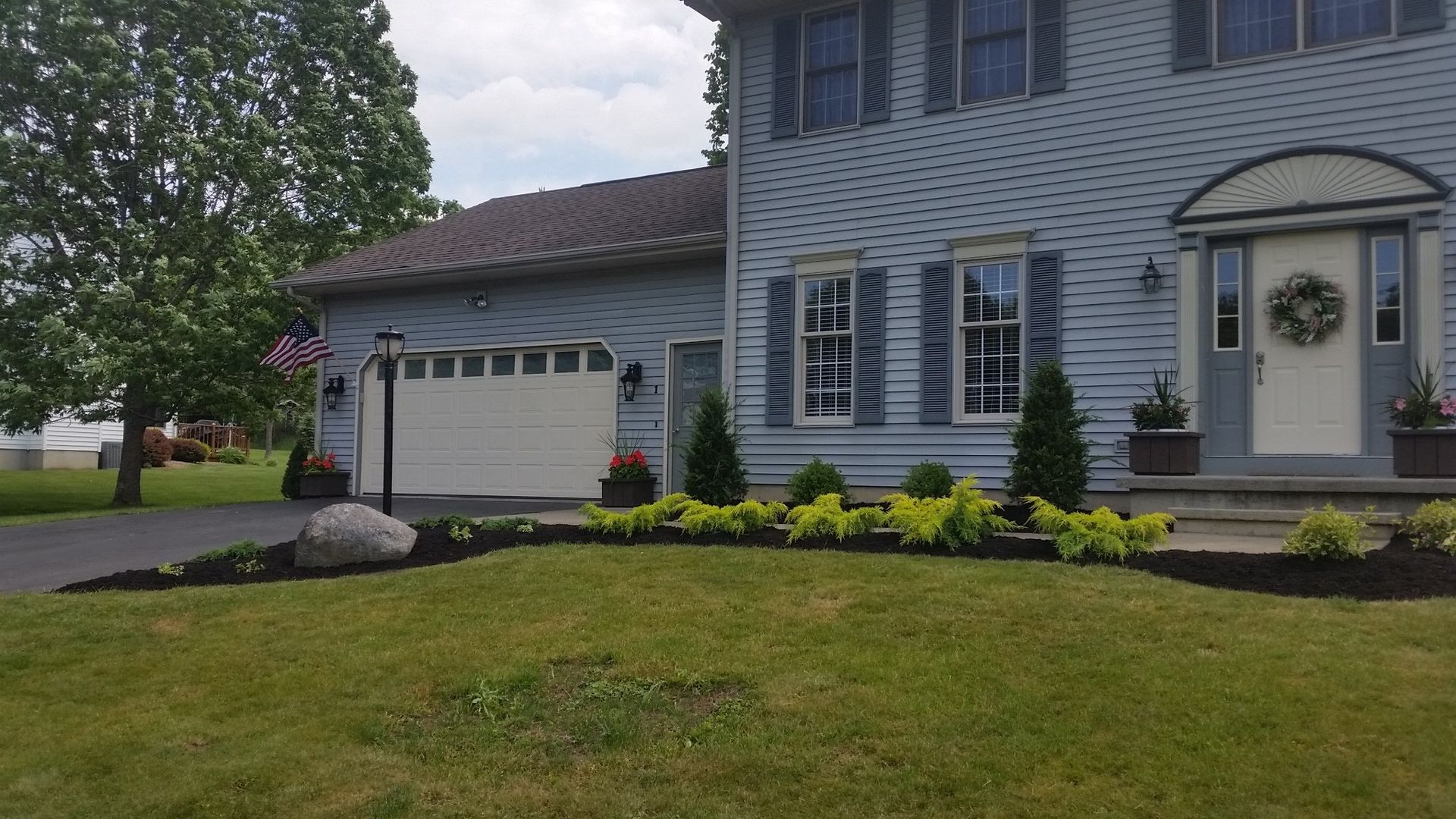 garage of blue house with flowerbed