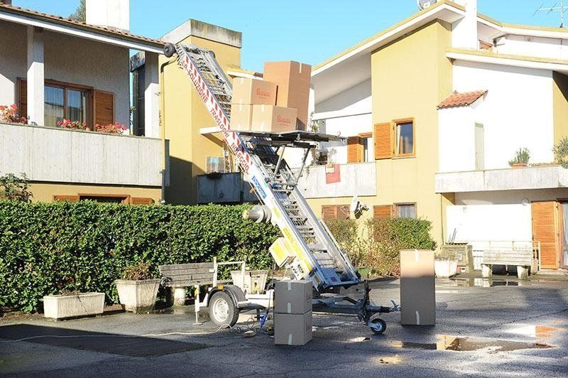 Un camion per traslochi con un elevatore che trasporta scatoloni in un edificio a più piani.