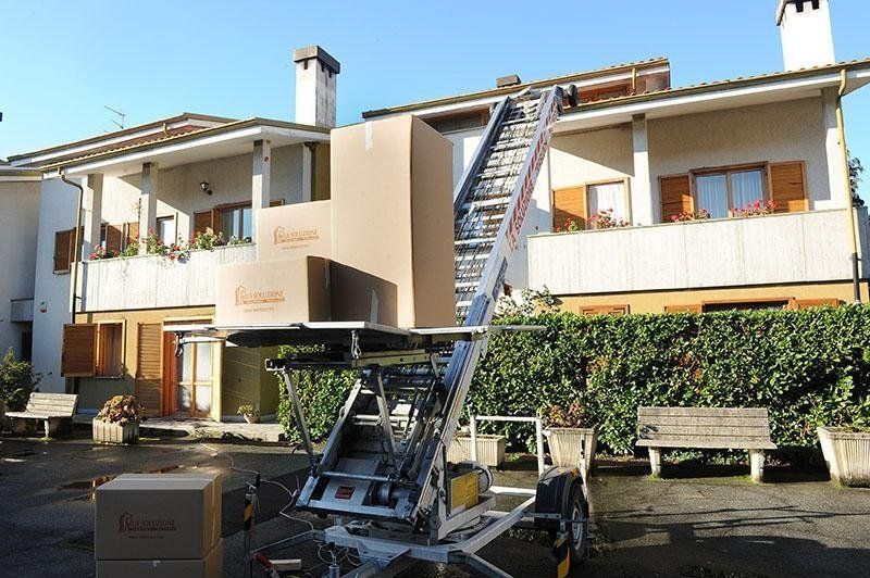 Un camion per traslochi dotato di piattaforma elevatrice solleva delle scatole