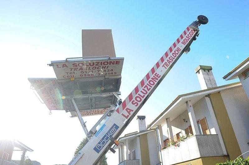 Un camion per traslochi con un elevatore esteso solleva una grande scatola di cartone