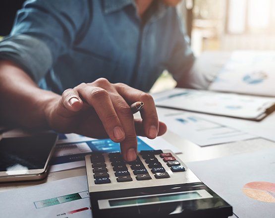 Business man using calculator — Troy, MI — Robert Bassman & Associates