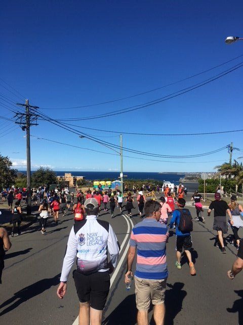 A group of people are walking down a street with the ocean in the background
