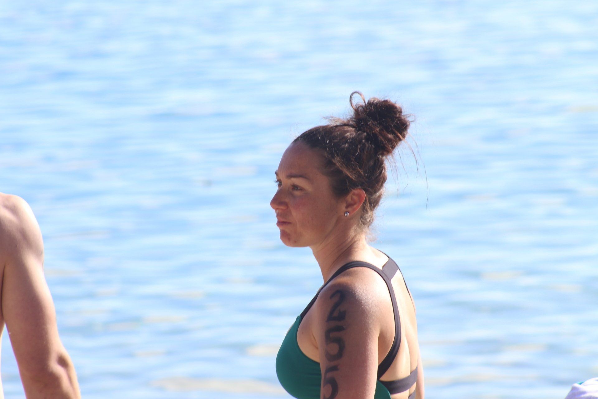 A woman in a green bikini is standing on a beach next to a man.