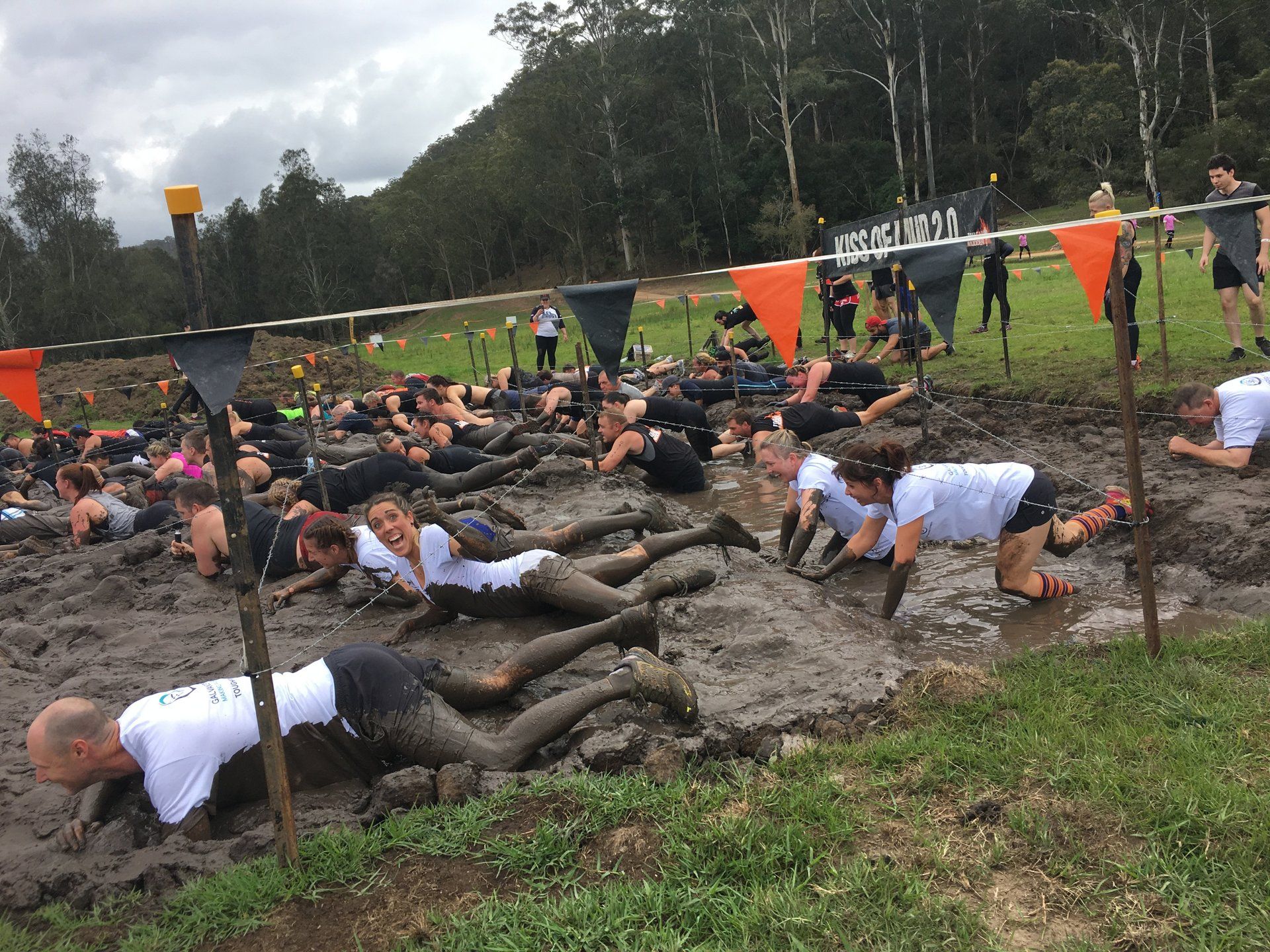 A group of people are doing push ups in the mud.