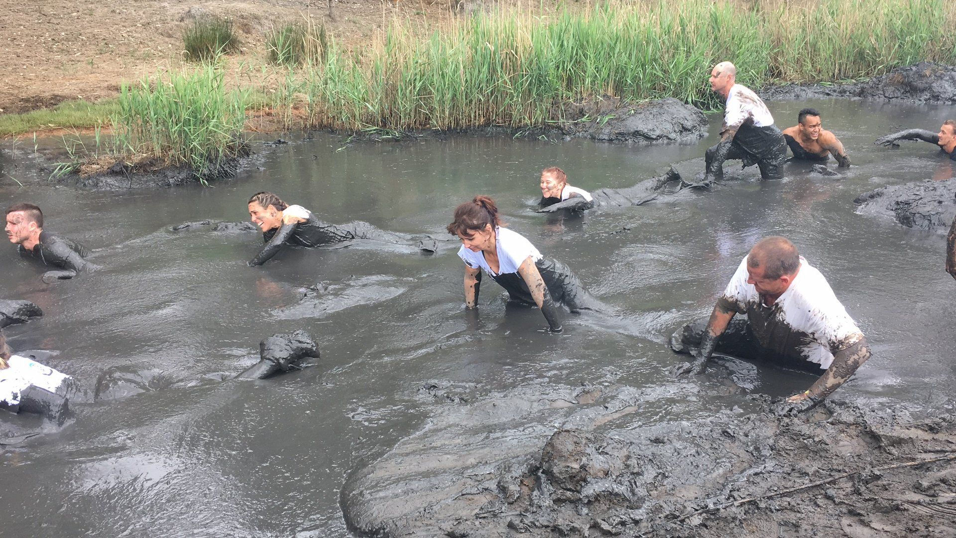 A group of people are crawling through a muddy river.
