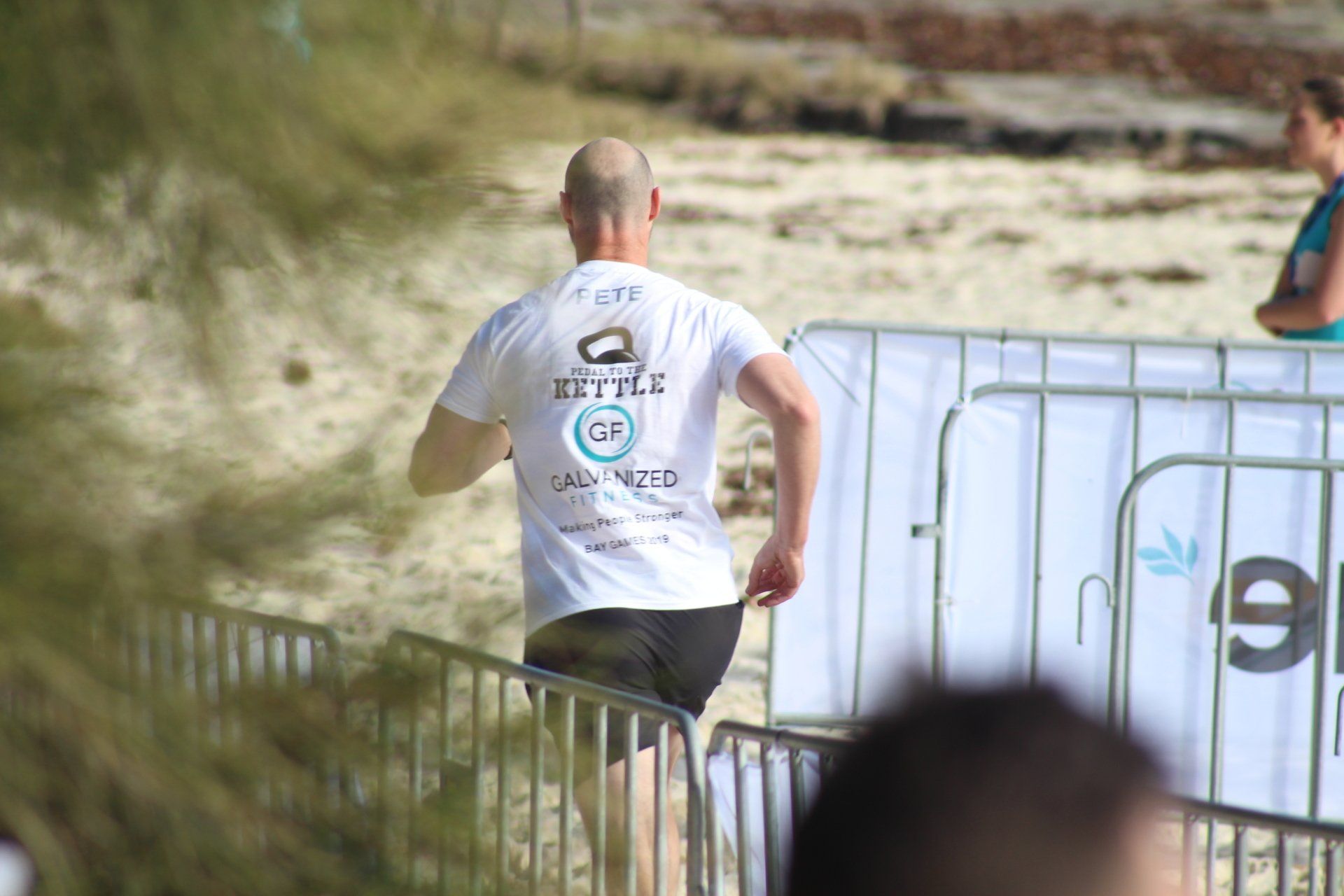A man in a white shirt is running on a beach.