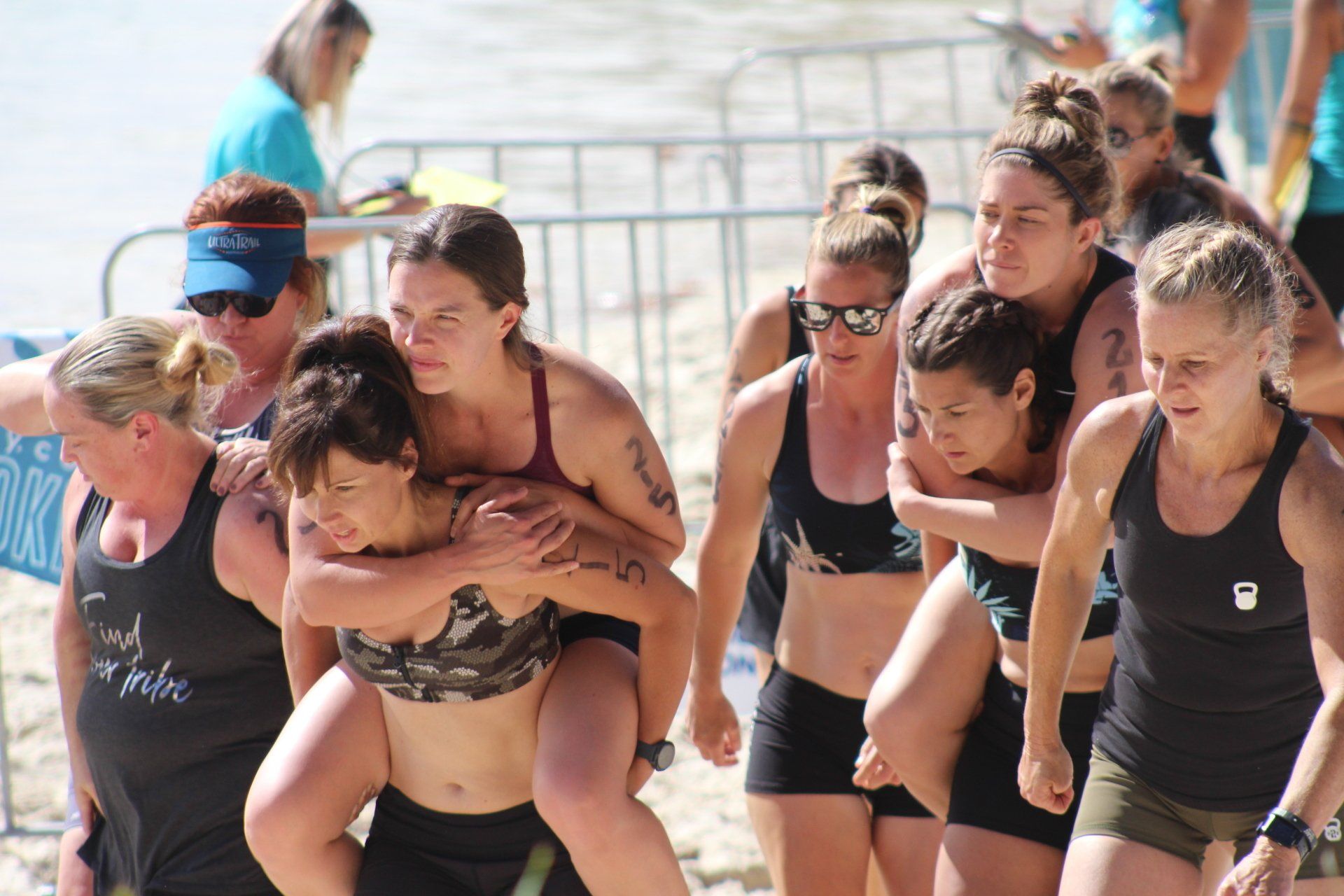 A group of women are carrying each other on their shoulders on a beach.