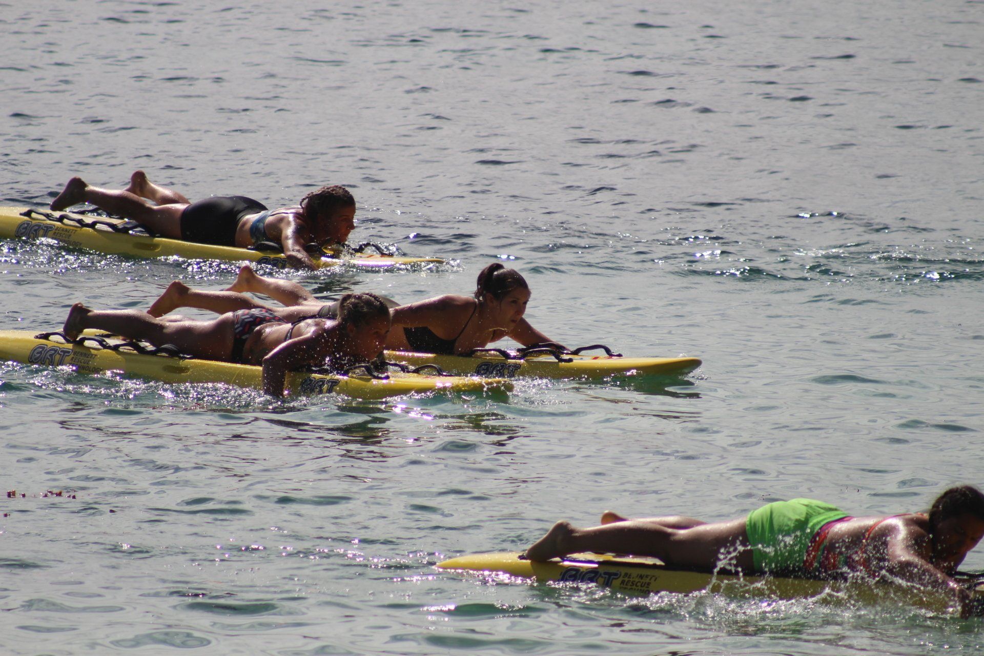 A group of people are laying on surfboards in the water