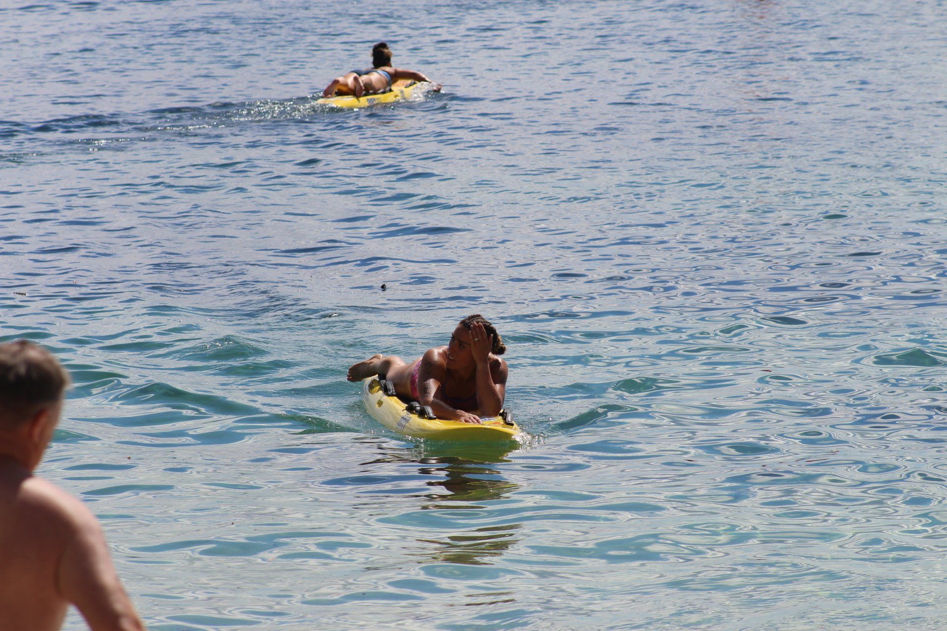 A woman is laying on a surfboard in the ocean.