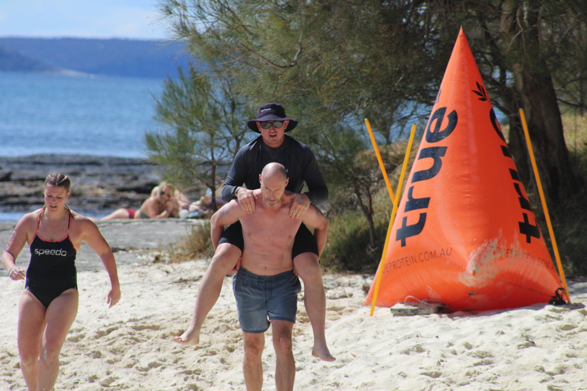 A man is carrying a woman on his shoulders on the beach.