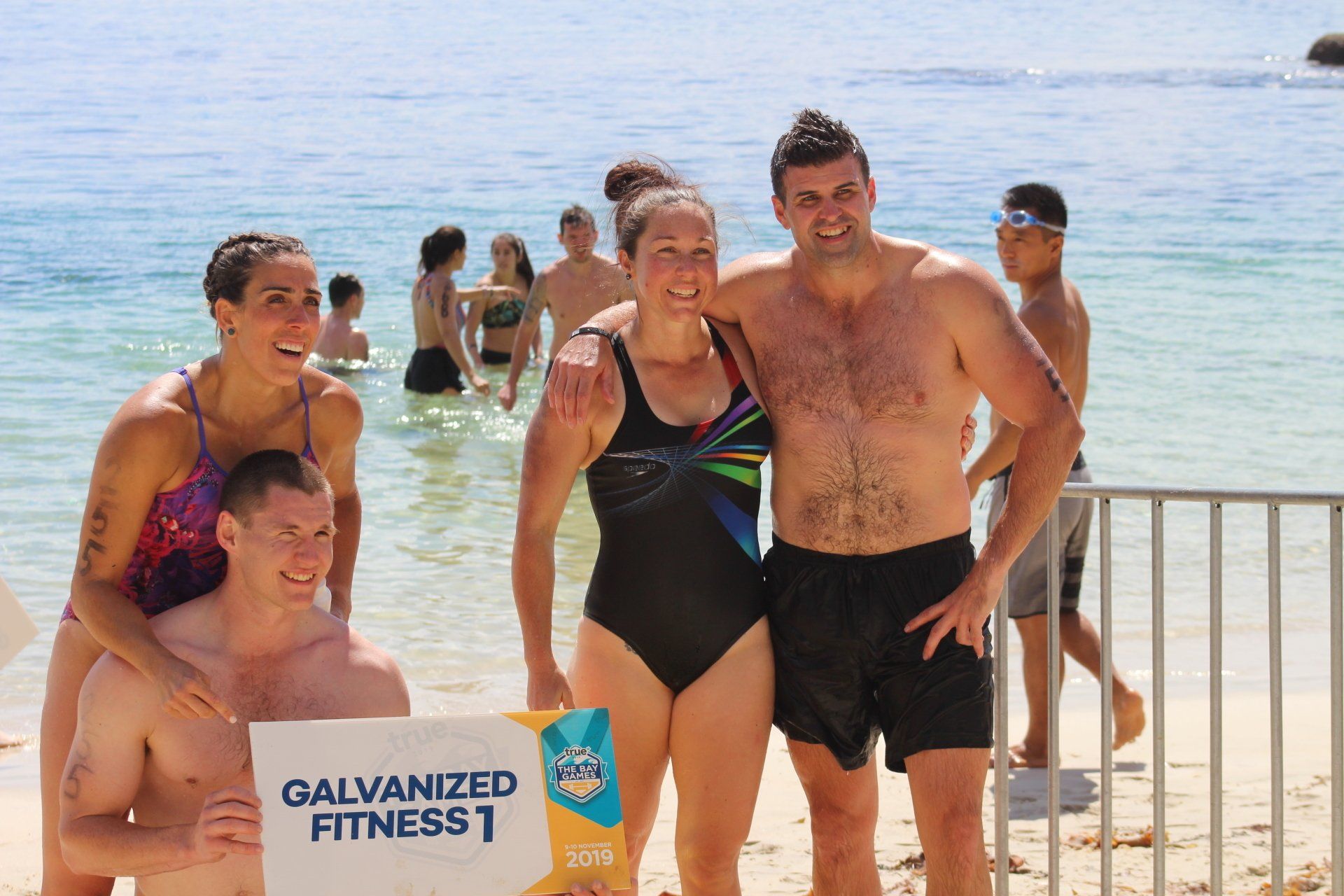 A group of people standing on a beach holding a sign that says galvanized fitness