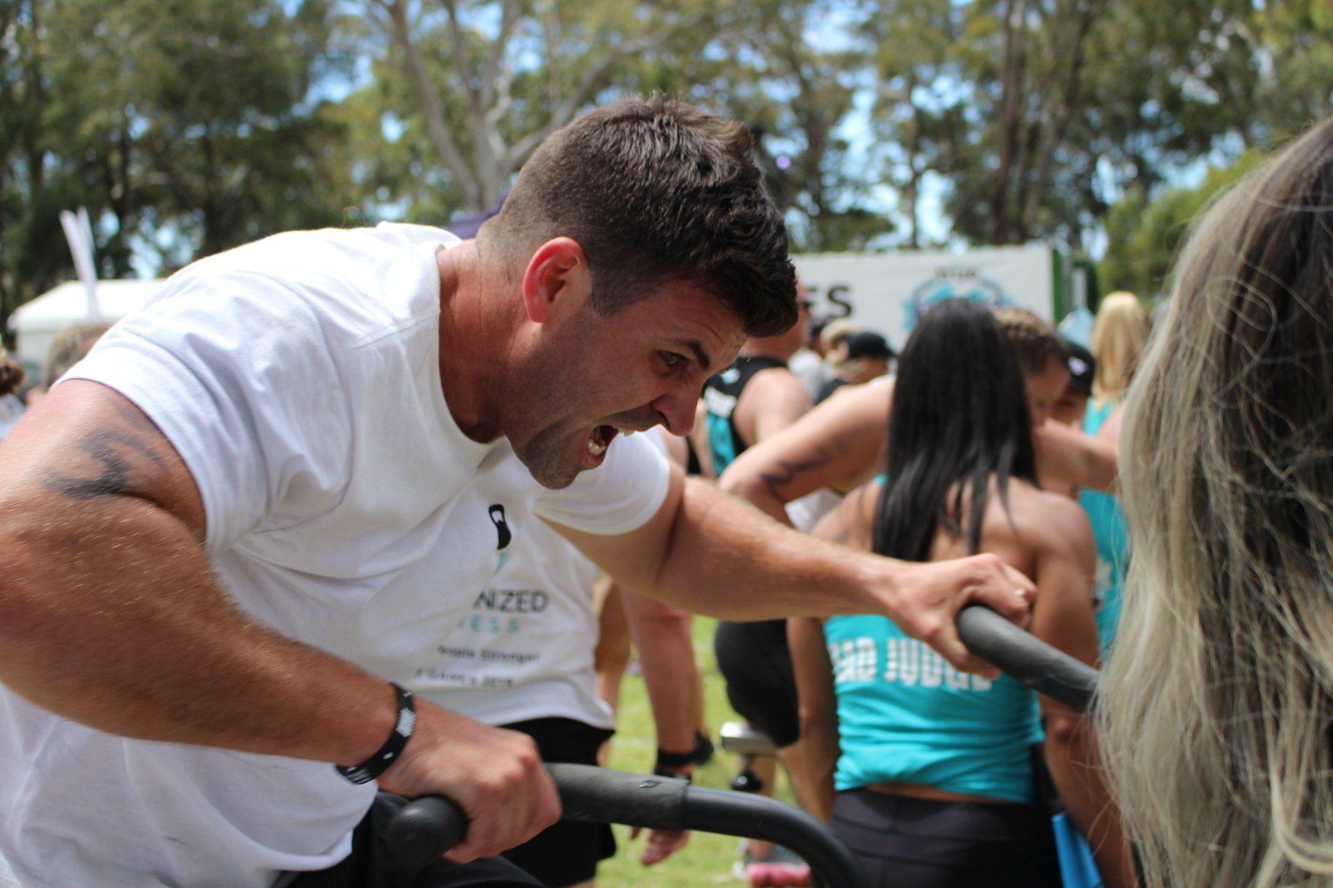 A man is riding an exercise bike in a crowd of people.