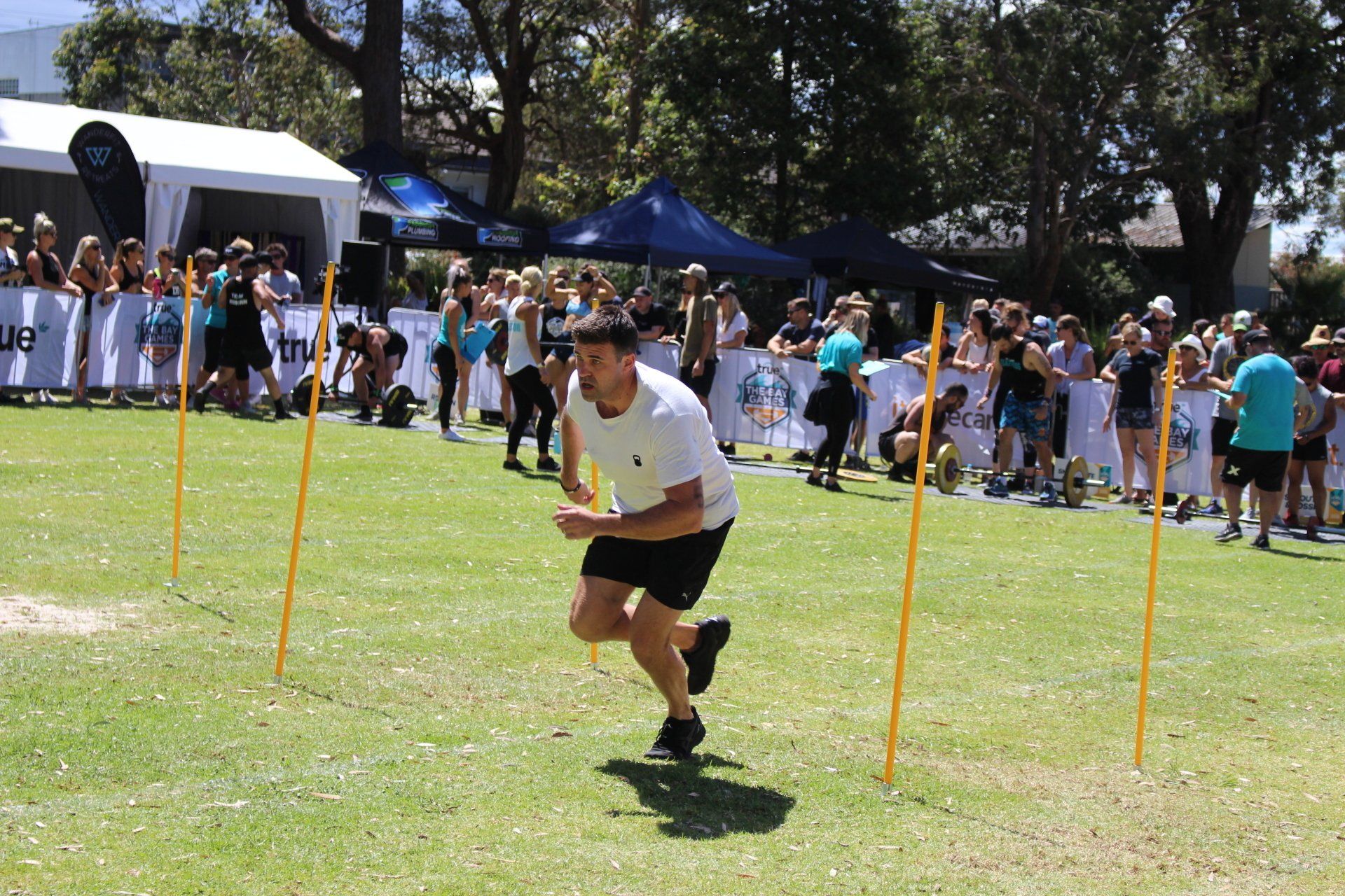 A man in a white shirt and black shorts is running on a grassy field.