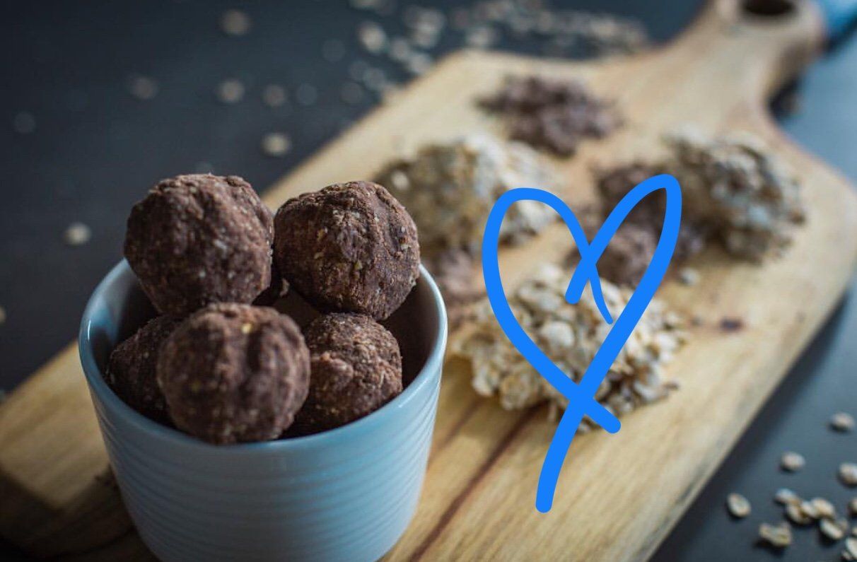 A bowl of chocolate balls is sitting on a wooden cutting board.